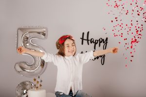 sesion de cumpleanos infantil en Corredor del Henares Thiago 5 anos con confeti rojo estilo superheroe en estudio