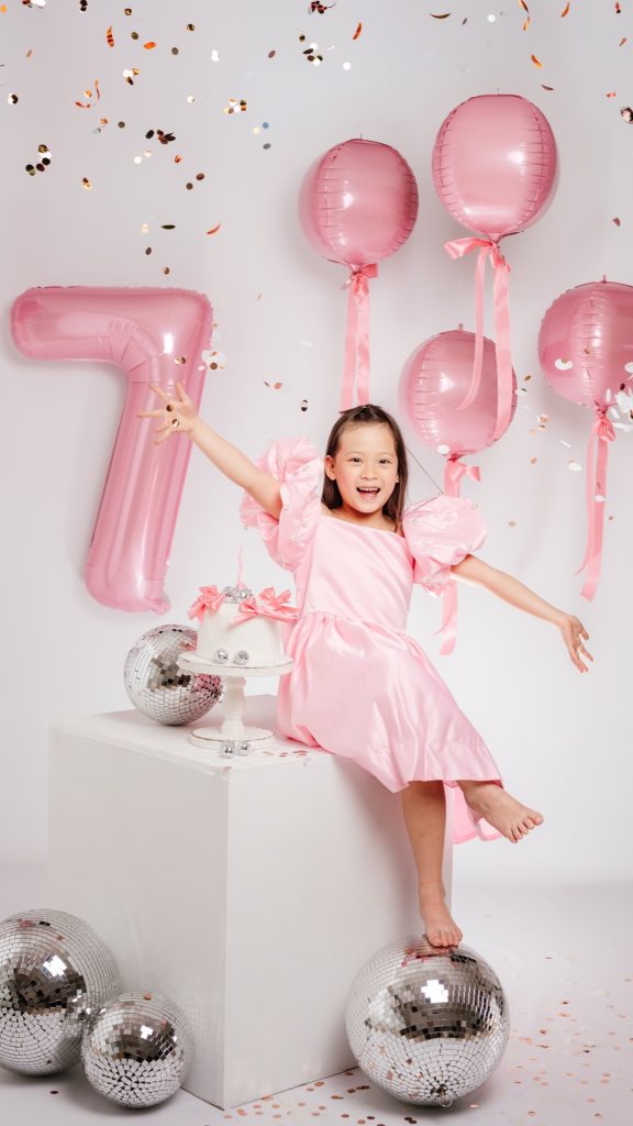 niña de 7 años sentada con globos y confeti en sesión de cumpleaños infantil en estudio en Madrid